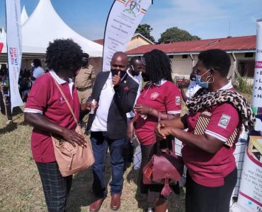 242858662_4550433495020512_6095018585112159349_n Women with hearing impairment in maroon and white collared t-shirts and black skirts standing around a man holding up the yes thumb sign